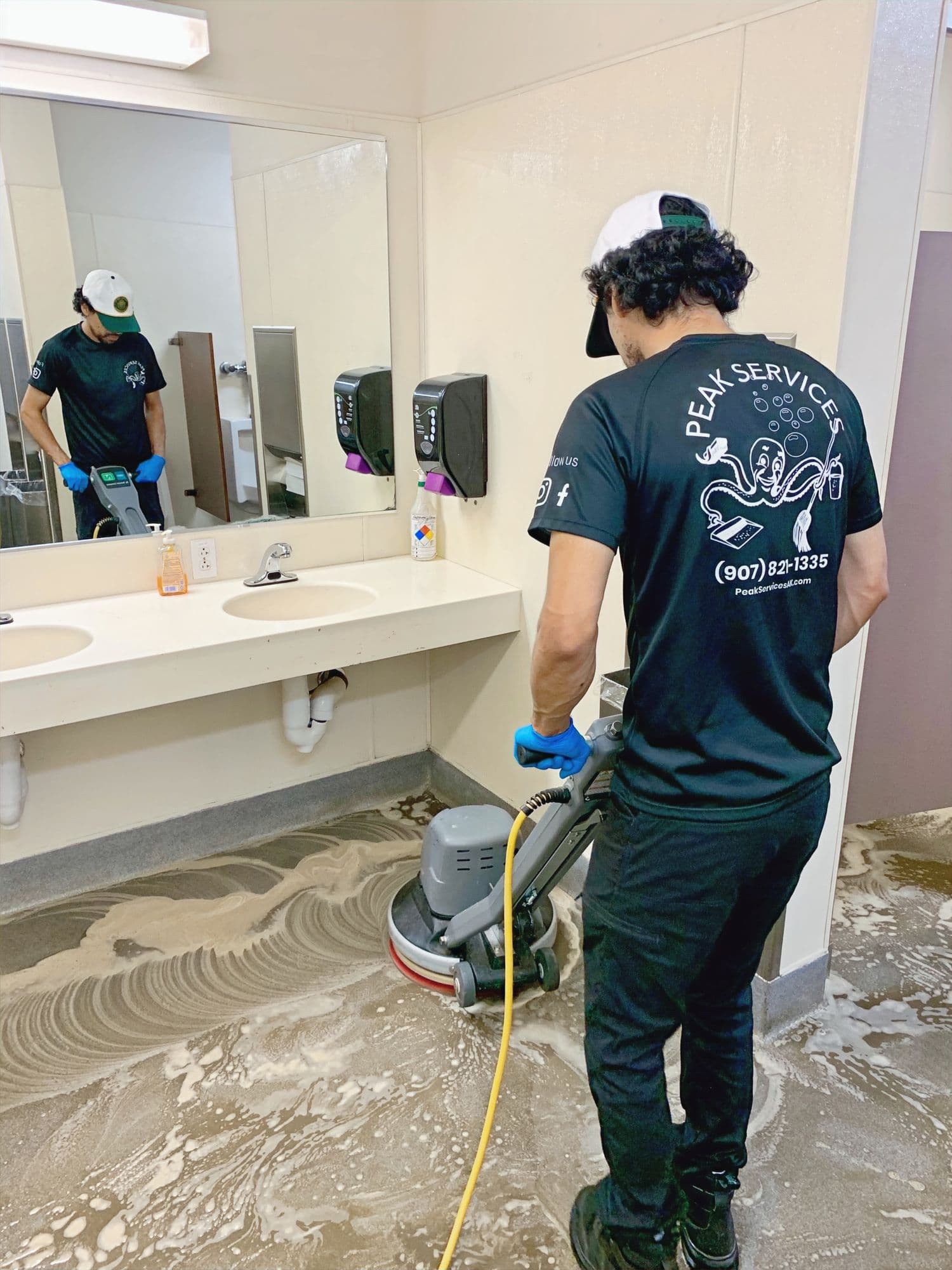 A Peak Services technician detailing a restroom floor